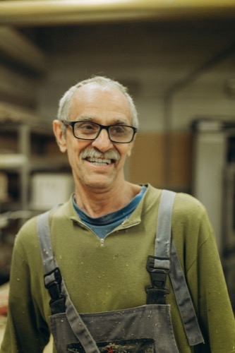 Smiling senior Ampcrest electrician in work overalls