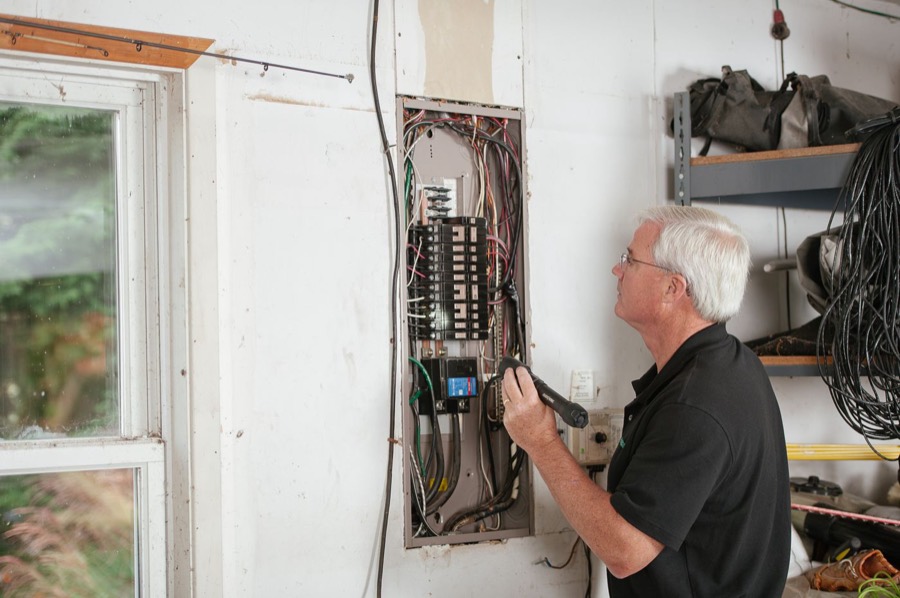 Electrician checking a residential breaker panel in a home