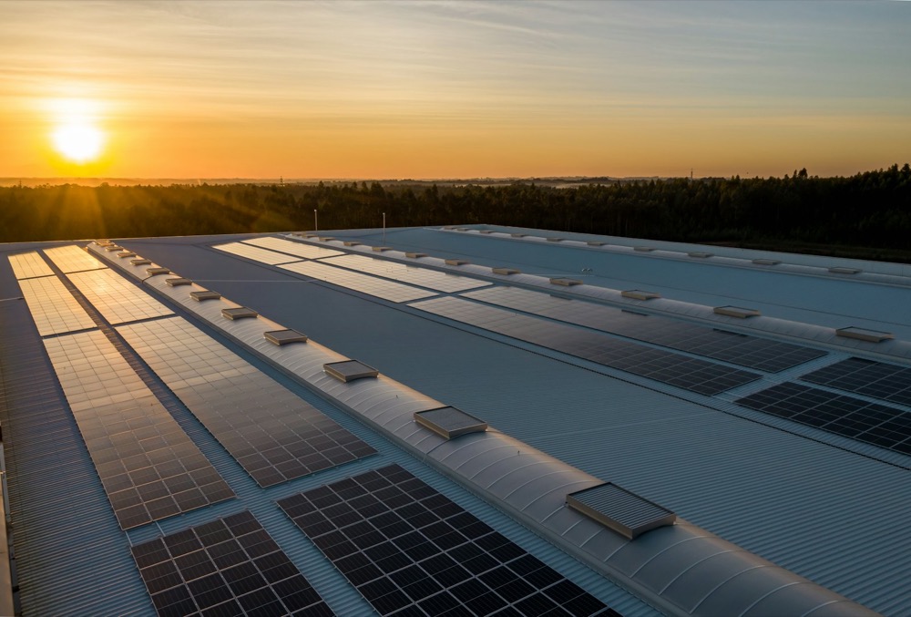 Solar panels on a large warehouse roof at sunset