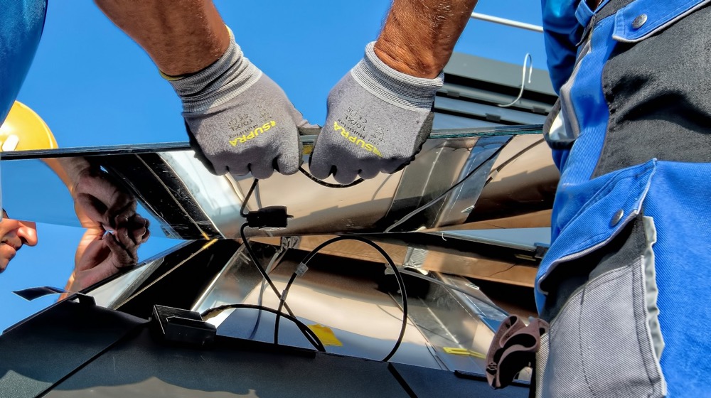Two installers fitting a solar panel on a roof